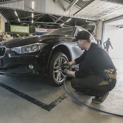 Asentaja vaihtamassa kesärenkaita henkilöautoon.
