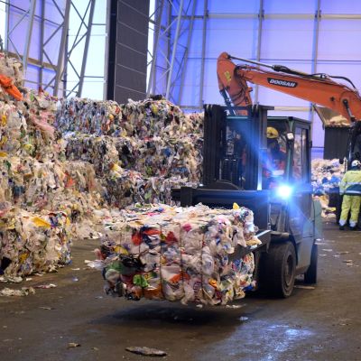 Kuva Fortumin muovinjalostamolta, jossa trukki kuljettaa kierrätysmuovipaaleja.