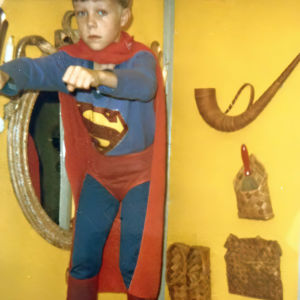 Tero Puha lapsena seisomassa valkoisen lipaston päällä, yllään Supermiesasu.