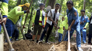 Thailändska räddningsarbetare gräver invid det övergivna lägret för att hitta rester av döda kroppar. Thailändska räddningsarbetare gräver för att hitta rester av kroppar.