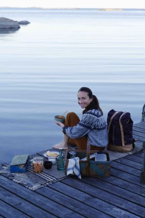 Hanna Olvenmark tycker om att utmana normerna, speciellt köttnormen. Att vegetarisk mat är bättre för klimatet är också en stor drivkraft. Det var ändå hennes egen ekonomi som ensamboende med hög hyra som startade allt. en kvinna sitter på en brygga vid havet och har mat och kärl runtom sig