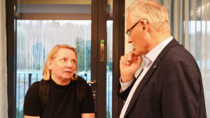 Tuula Ojaluoma och Hans Blomberg. En kvinna och en man diskuterar. De ser fundersamt på varandra.