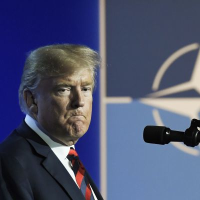 USA:s president Donald Trump i bakgrunden syns militäralliansen Natos symbol