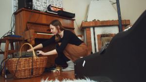 I Laura Naukkarinens hus finns både träningsutrymmen och studio. Laura Naukkarinen sitter på huk och plockar i en korg full med sladdar.