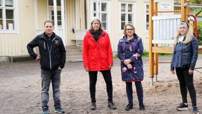 Fyra personer står framför en skolbyggnad.