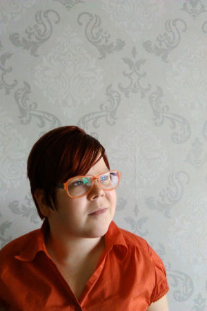 Eri älskar sitt nya androgyna liv. Eri Lassila iklädd en orange skjorta och orange glasögon.
