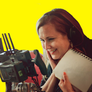 Anna Dahlman katsoo nauraen monitoriin keltaisessa kuvassa.
