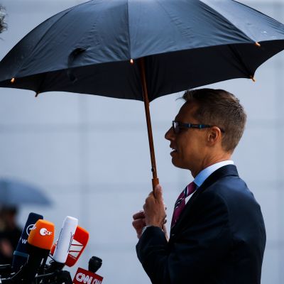 Sivusta otettu valokuva Alexander Stubbista sateenvarjon alla.