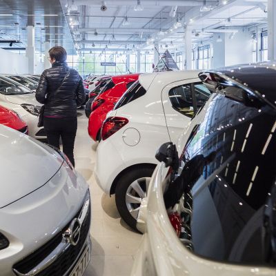 Nainen katselemassa käytettyjä autoja autoliikkeessä.