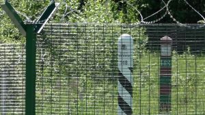 Bakom gränsstaketet syns en estnisk och en rysk gränsstolpe. Den tio meter breda gränszonen är alltså på den estniska sidan av gränsen. Bakom gränsstaketet syns en estnisk och en rysk gränsstolpe.