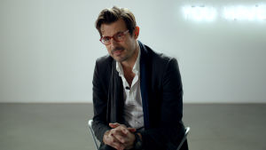Förstår du inte modern konst, lilla vän? tycks Christian (Claes Bang) tänka när han sitter och blir intervjuad. Närbild på Christian (Claes Bang).