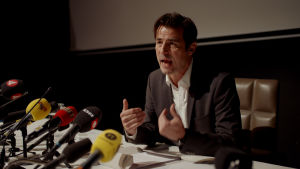 Christian (Claes Bang) försöker förklara vad han gjort och inte gjort. Christian (Claes Bang) sitter på en presskonferens och försöker förklarar.