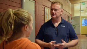 Anders Strömsund ser skola i rörelse som ett bra initiativ. Anders Strömsund talar med några elever i en skolkorridor.