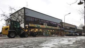 Fastighetsägarna ville inte ha möjligheten till en stormarknad på tomten. Slitna affärsbyggnader från 1960- eller 1970-talet. En liten snötraktor kör på gatan. En grå vinterdag, lite is och snö på gatan.