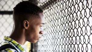 Den tonåriga Chiron (Ashton Sanders) känner sig alltmer ensam och utlämnad. Chiron (Ashton Sanders) står vid ett nätgaller och tittar.