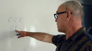 Spannet för hur mycket klimatet värms upp av en viss mängd koldioxid bara växer. John Hassler pekar mot några siffror och bokstäver han antecknat på en whiteboard.