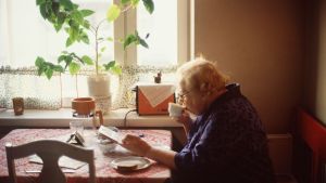Servicedirektör Helena Räsänen hoppas att de äldre i Sibbo ska svara i telefon trots att samtalet kanske kommer från okänt nummer. Äldre dam sitter i köket och dricker kaffe