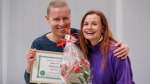Nicke Aldén ja Hannamari Hoikkala Helsingin messukeskuksessa palkintojenjaon jälkeen. Mies ja nainen poseeraavat iloisesti diplomin ja kukkakimpun kera.