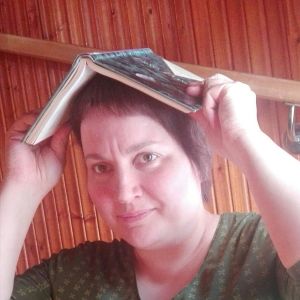 Kirjakko ruispellossa -blogin Mari Saavalainen pitää kirjaa päänsä päällä.