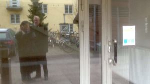 På Rautalampivägen är allt nästan som förr Två personer speglas genom glasdörr