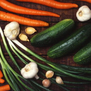 Morötter, purjolök, zucchini och vitlök på ett bord.