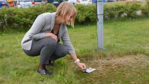 "Mösset", sensorn som mäter hur varm marken är. En kvinna står på huk utomhus bredvid ett litet mätinstrument.