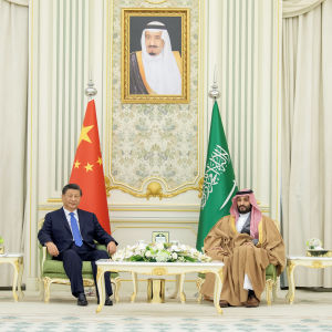Kinas president Xi Jinping och Saudiarabiens kronprins Mohammed bin Salman  sitter i varsin fåtölj med sina länders flaggor bakom sig. Mellan dem står ett bord i antik stil med en blomsteruppsättning på.