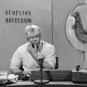 Spede Pasanen pelleilee Iskelmäkarusellissa "Kuopijon höyryradion" juontajana.