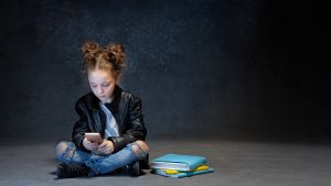 Nu är det helt okej att sitta med skärm när man gör skolarbete. ett barn tittar på mobiltelefonen i ett mörkt rum