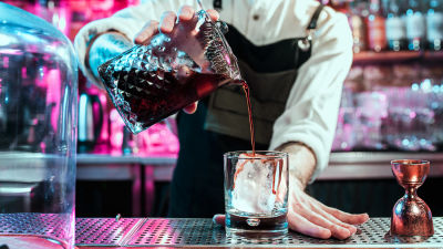 en barmästare blandar en drink som verkar ha något syrligt och isigt i sig