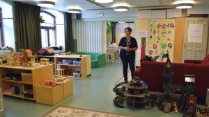 Förskolan finns i Eftis uppdaterade lokaler. En barnpedagog står mitt i förskolans lekrum fyllt med leksaker och skåp.