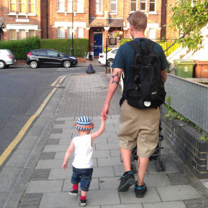 Petteri Pykäläinen kävelee käsi taaperoikäisen lapsen kädessä lontoolaiskadulla.