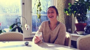Kollektivboendet känns som den rätta boendeformen för Cecilia Weckström. Cecilia Weckström sitter på en glasveranda och ler med tänderna.