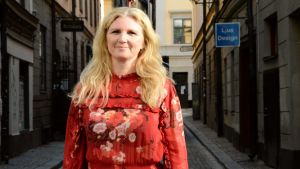 Maria Flock Åhlander tycker inte att Ekobanken är ett naivt koncept. Maria Flock Åhlander i röd klänning står i en gata i gamla stan i Stockholm.