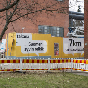 Ett skyddsstaket, en gul skyddsvägg med text och tegelväggar.