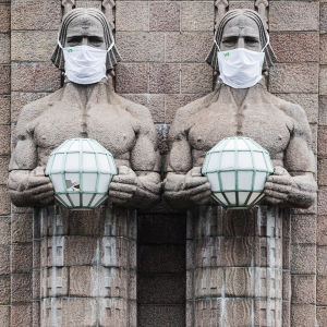 I bild syns en skulptur "Lyktbärare" utanför Helsingfors tågstation som bär munskydd.