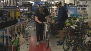 Marcus Davidsson föredrar vanliga cyklar, utan el, för att få bättre motion. Nu har han investerat i en ny vintercykel. Cykelförsäljare fixar på en cykel medan kunden med cykelhjälm väntar.