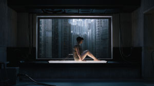 Major (Scarlett Johansson) sitter invid ett fönster, i bakgrunden skyskrapor.