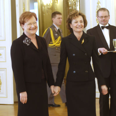 Tarja Halonen håller Anneli Jäätteenmäki i handen och båda ler.