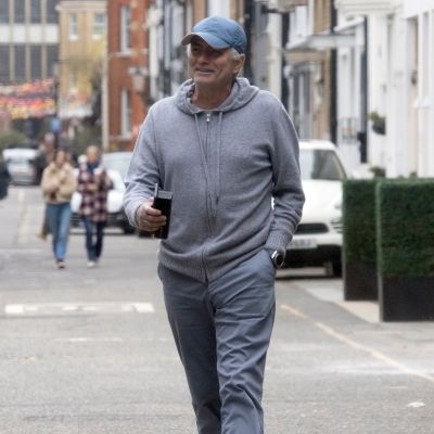 José Mourinho i casual-kläder (grå byxor, grå munkjacka) skrattande på en gata i London.
