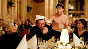 Kiusallisia hetkiä: apinamies (Terry Notary) lähestyy taiteilijaa (Dominic West). Apinamies häiritsee illallisseuruetta. Kohtaus elokuvasta The Square.