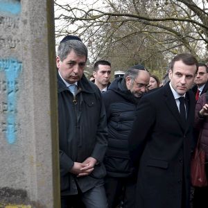 Emmanuel Macron bredvid en judisk grav som någon målat ett hakkors på.