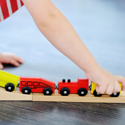 Barn som leker med leksak, ett tåg och tågvagnar gjorda i trä.