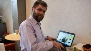 Deniz Söderström förevisar framtidens skördemaskiner för vass. Deniz Söderström står vid en dator.