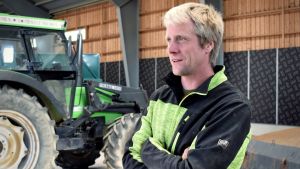 Enligt Claus Blomberg är det allt viktigare att markstrukturen är i skick i fall vädret blir mer extremt i framtiden. Claus Blomberg står i en lagerhall framför en grön traktor.