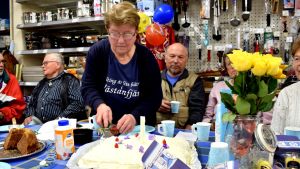 Runa Heino skär upp kakan som dukades upp ettårsdagen till ära. Runa Heino skär upp tårta i bybutiken Knallis.