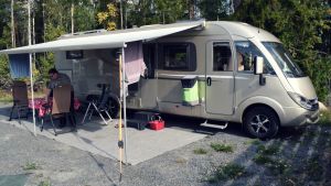 En rymlig husbil, men i Spanien var Lindströms bil i största laget för där är det trångt om utrymme. En stor husbil med ett soltak på en grusplan .