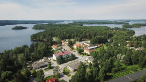 Kahvila Korppu ja Vanha rouva pitävät majaa punakattoisessa kivitalossa keskellä Sumiaisen kylää Keski-Suomessa. Ilmakuva kylästä kahden järven kannaksella.