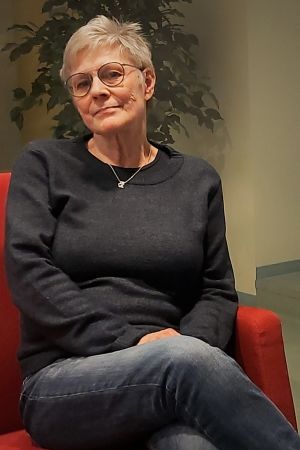 Tove Karlsson arbetade med ungdomar i Borgå i 40 år. Medelålders kvinna poserar i en röd soffa.