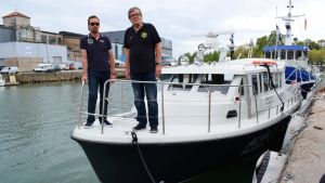 Båten som ska ta ut turister på historiska rundturer från Dalsbruk i sommar. Calle Storm och Niklas Löfberg står på fören av en vit passagerarbåt.